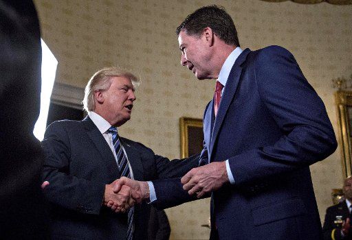 U.S. President Donald Trump, left, shakes hands with James Comey, director of the Federal Bureau of Investigation (FBI), during an Inaugural Law Enforcement Officers and First Responders Reception in the Blue Room of the White House in Washington, D.C. on January 22, 2017. Trump today mocked protesters who gathered for large demonstrations across the U.S. and the world on Saturday to signal discontent with his leadership, but later offered a more conciliatory tone, saying he recognized such marches as a Òhallmark of our democracy.Ó Pool photo by Andrew Harrer\/