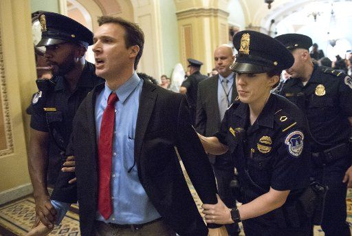 Ryan Clayton is arrested after throwing Russian flags at President Donald Trump as he arrives for a Republican Senate luncheon meeting, at the U.S. Capitol Building on October 24, 2017, in Washington, D.C. Photo by Kevin Dietsch\/
