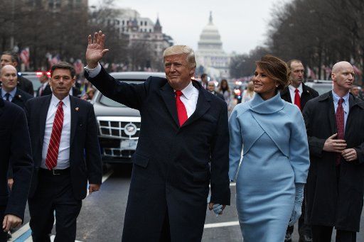 President Donald Trump and First Lady Melania Trump acknowledge the crowds as they walk in their inaugural parade in Washington, D.C. on January 20, 2017. Trump was sworn in as the 45th President of the United States. Pool photo by Evan Vucci\/