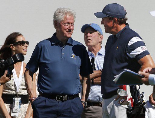 Former U.S. President Bill Clinton talks with Phil Mickelson of the United States as former U.S. President George Bush stands behind them at the first tee box on day one of the Presidents Cup on September 28, 2017 at Liberty National Golf Club in Jersey City, New Jersey. Photo by Rich Schultz\/