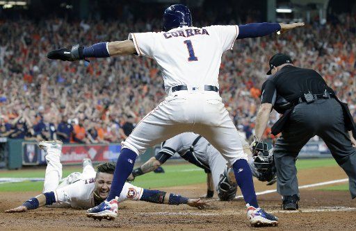 Houston Astros Yuli Gurriel (L) scores against New York Yankees catcher Gary Sanchez in the fifth inning on a double by teammate Brian McCan in game 7 of the American League Championship Series at Minute Maid Park in Houston, Texas on October 21, 2017. Astros Carlos Correa (1) who scored just prior to Gurriel signals safe next to home plate umpire Mark Carlson. The Yankees-Astros winner will advance to the World Series to play the Los Angeles Dodgers. Photo by John Angelillo\/