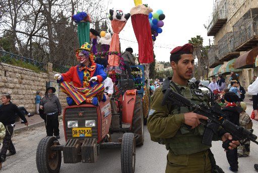 An Israeli soldier guards Jewish settlers wearing costumes in the annual Purim parade in Hebron, West Bank, to celebrate the Jewish holiday of Purim, on March 12, 2017. The festival of Purim commemorates the salvation of the Jewish people from Haman\