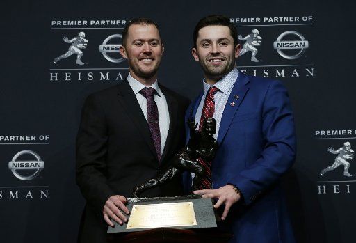 Oklahoma quarterback Baker Mayfield holds the Heisman Trophy with Oklahoma coach Lincoln Riley at the Marriott Marquis in New York City on December 09, 2017. Mayfield wins the 2017 Heisman Trophy award beating out other finalists Louisville quarterback Lamar Jackson and Stanford runningback Bryce Love. Photo by John Angelillo\/