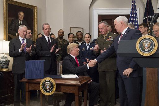 President Donald Trump shakes hands with Vice President Mike Pence after signing H.R. 2810, the National Defense Authorization Act for Fiscal Year 2018, during a signing ceremony in the Roosevelt Room on December 12, 2017 in Washington, D.C. Trump was joined by, from left to right, Defense Secretary Jim Mattis, Chairman of the House Armed Services Committee Mac Thornberry, R-TX, Chairman of the Joint Chiefs of Staff Joseph F. Dunford, and members of the military. Photo by Kevin Dietsch\/
