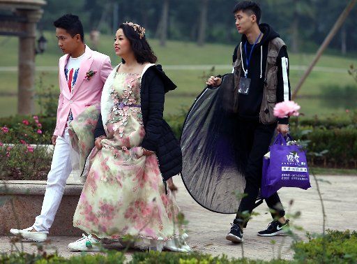 A young Chinese couple walks through a park on their way to a wedding photo shoot near Beijing on December 13, 2017. Attitudes about traditional Chinese marriage have been influenced by Western countries, with more couples nowadays opting for Western-style weddings. Photo by Stephen Shaver\/