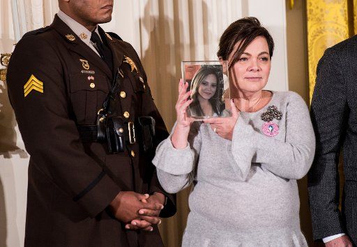 A woman holds a photo of a loved one lost to the opioid epidemic during an event where President Donald Trump delivered remarks on the opioids and labeled the opioid crisis a public health emergency, in the East Room at the White House in Washington,...