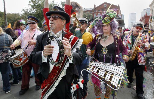 Members of a marching group calling itself the Krewe of Cosmic Debris parade past Jackson Square in New Orleans\