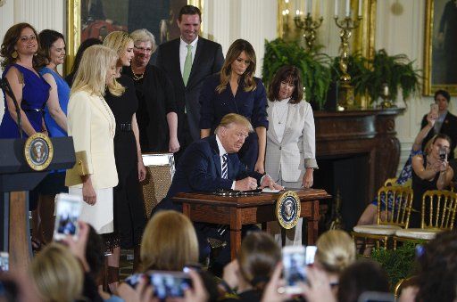 President Donald Trump signs an exectuive order during the Celebration of Military Mothers and Spouses in the East Room of the White House in Washington, D.C on May 9, 2018. Photo by Leigh Vogel\/