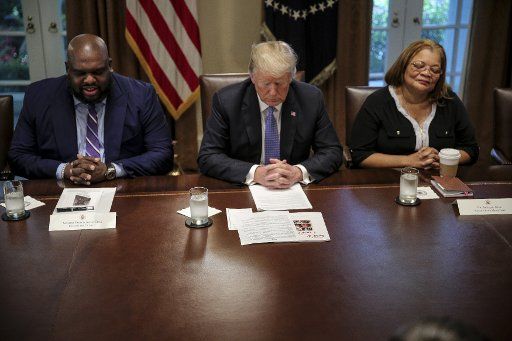 President Donald Trump bows his head during a meeting with inner city pastors in the Cabinet Room of the White House on August 1, 2018 in Washington, DC. At left is Relentless Church Pastor John Gray. They discussed prison reform and other issues. Photo by Oliver Contreras\/
