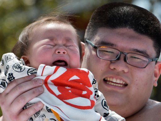 A baby held by an amateur sumo wrestler cries during the "baby crying contest (Naki Sumo)" at the Sensoji temple in Tokyo, Japan on April 28, 2019. This contest takes place for parents wishing good health and strength for children since 1986. Photo by Keizo Mori\/