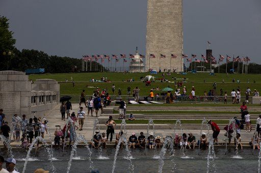 Tourists sit at the fountain of the World War II Memorial on Independence Day on the National Mall in Washington, D.C. on Thursday, July 4, 2019. Photo by Anna Moneymaker\/