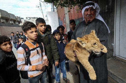 A Palestinian man holds a lion cub for children along a street in Rafah in the southern Gaza Strip on Tuesday, December 3, 2019. Photo by Ismael Mohamad\/