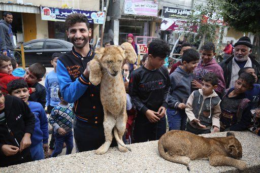 A Palestinian man holds up a lion cub for children along a street in Rafah in the southern Gaza Strip on Tuesday, December 3, 2019. Photo by Ismael Mohamad\/