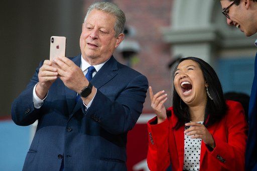 Al Gore (L) environmentalist and former United States Vice President takes a photo while Harvard senior Catherine Zhang laughs before Gore gives the 2019 Harvard University Class Day address in the tercentenary theatre on the campus of Harvard University in Cambridge, Massachusetts, on May 29, 2019. Gore called on Harvard to divest from fossil fuels during his speech. Photo by Matthew Healey\/