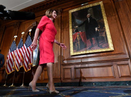 Newly-elected Speaker of the House Nancy Pelosi walks from one swearing-in photo op to the next in the Rayburn Room in front of a portrait of America\