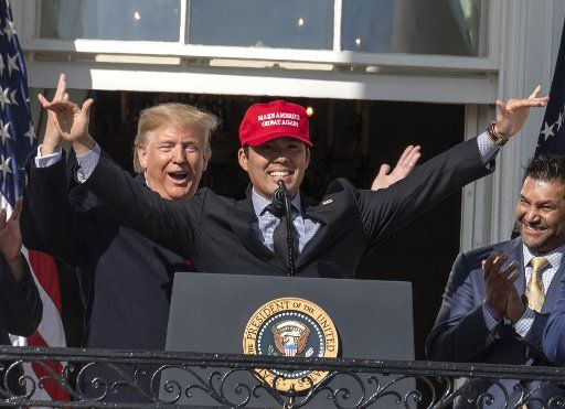 President Donald Trump smiles as Washington Nationals player Kurt Suzuki wears a "Make America Great Again" hat during a ceremony for the World Series Champions on the Truman Balcony at the White House on Monday, November 4, 2019. Nationals Manager Dave Martinez applauds at right. Photo by Pat Benic\/