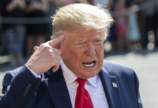 President Donald Trump points to his head as he responds to a reporter\