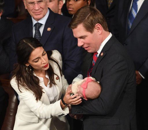 Rep. Alexandria Ocasio-Cortez (D-NY) chats with Rep. Eric Swalwell (D-CA) as he holds his new daughter Kathryn Watts Swalwell at the 116th U.S. Congress in the House Chamber on Capitol Hill in Washington, D.C. on January 3, 2019. Swalwell\