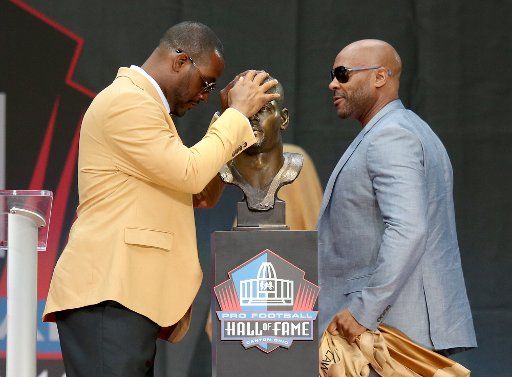 Ty Law (L) puts his hands on his bust as his presenter Byron Washington during his induction into Football Hall of Fame at Tom Benson Hall of Fame Stadium in Canton, Ohio, on August 3, 2019. Photo by Aaron Josefczyk\/