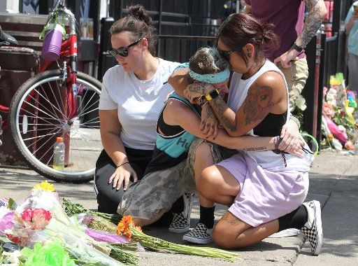 Friends console one another as they pay their respects to the nine victims of a mass shooting outside Ned Peppers bar on Monday, August 5, 2019, in Dayton, Ohio. Photo by John Sommers II\/