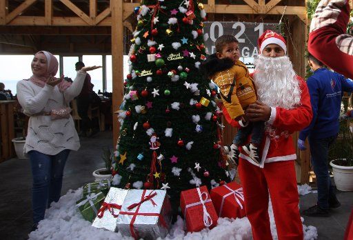 A Palestinian waiter, dressed as Santa Claus, serves customers at "Maldive Gaza" cafe on a beach in Gaza City, Sunday, December 13, 2020. Photo by Ismael Mohamad