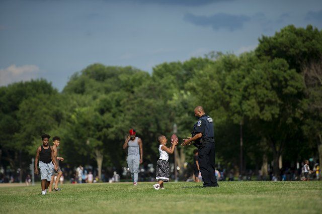 Members of the Metropolitan Police Department join a game of touch football as people gather to celebrate America\