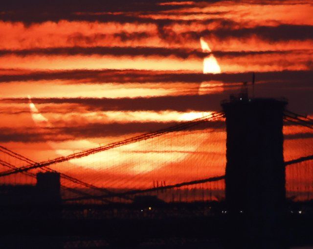 A partial solar eclipse rises behind the Brooklyn Bridge and other east river crossings in Manhattan from Bayonne, New Jersey on Thursday, June 10, 2021. Photo by John Angelillo