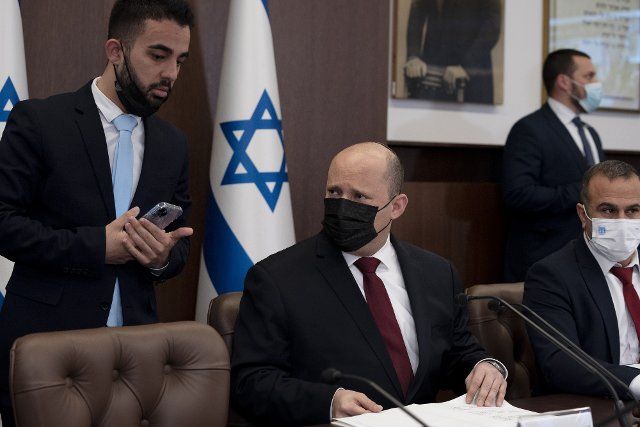 Israeli Prime Minister Naftali Bennett, center, confers with an aide as he chairs the weekly cabinet meeting in Jerusalem, Sunday, March 20, 2022. Pool Photo by Maya Alleruzzo