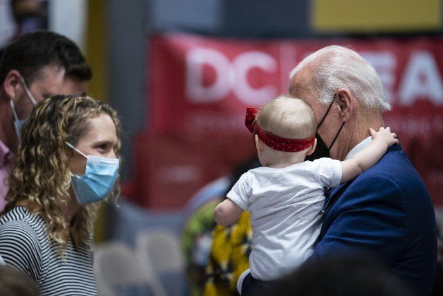 US President Joe Biden holds an infant while visiting a Covid-19 vaccination site hosted by the District of Columbia\