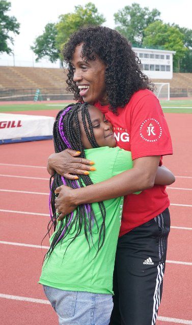 Six-time Olympic Medalist Jackie Joyner-Kersee hugs a participating child before a run on the campus of Washington University in St. Louis on Wednesday, June 22, 2022. Jackie Joyner-Kersee and other St. Louis Olympians lead hundreds of St. Louis area youth around the track at Francis Olympic Field, site of the 1904 Olympic Games, in observance of World Olympic Day. Photo by Bill Greenblatt