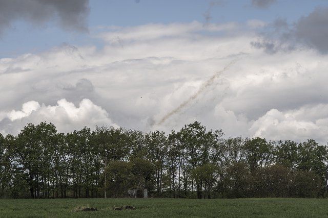 Smoke from a Ukrainian launch (unknown type) is seen in the sky as Ukrainian soldiers, (out of frame), prepare to lift a destroyed Ukrainian 2S7 Pion (Peony), tank lying in a field from Russian shelling two nights before east of Kharkiv in Vilhivka, Ukraine, Sunday, May 15, 2022. Photo by Ken Cedeno