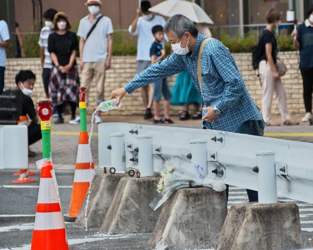 A man pray and sprinkle water laid at the site where late former Japan\