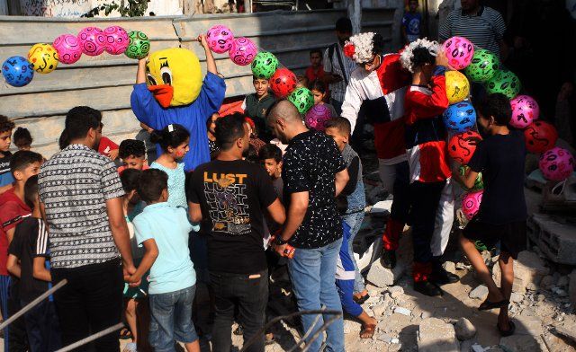 Palestinian children are entertained by clowns amidst the rubble of a building destroyed by Israeli air strikes in Rafah in the southern Gaza Strip on Tuesday on August 9, 2022. An Egypt-brokered ceasefire reached late on August 7 ended the intense fighting that killed 46 people including 16 children and wounded 360 in the enclave, according to Gaza\