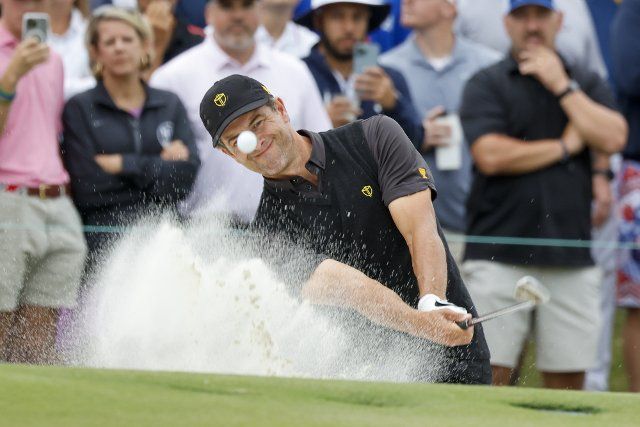 Adam Scott, of Australia, hits out of the bunker on the fourth hole in the President\