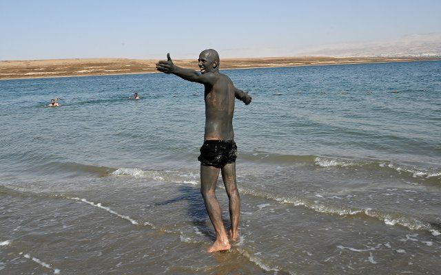 A visitor covered in black mud enters the Dead Sea at the Biankini Village Resortâs private beach in the West Bank near Jericho, on Thursday, September 29, 2022. Israeli owner, Dina Dagan says 80% of her bookings are made through Booking.com and that she is seeing a drop in reservations since Booking.com, the online travel agency announced that it will add warnings to listings in the Israeli occupied West Bank, cautioning customers reserving accommodations in Israeli Settlements that they are traveling to a disputed high risk area. Israeli Tourism Minister Yoel Razvozov says he\