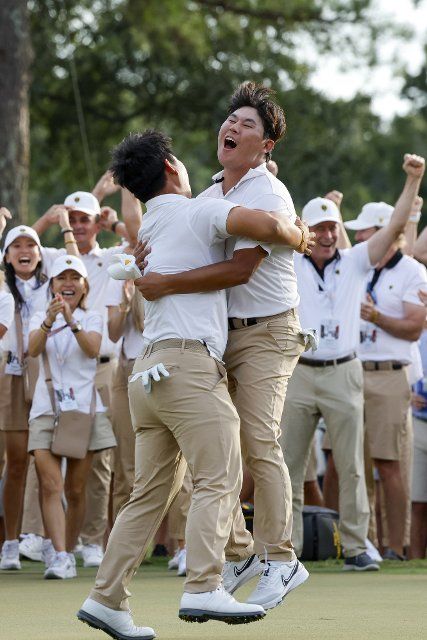 Tom Kim, of South Korea, left, hugs teammate Si Woo Kim, of South Korea, after Tom Kim made a birdie putt to win a point for the International team during four-ball match play at the Presidents Cup golf championship in Charlotte, North Carolina on Saturday, September 24, 2022. Photo by Nell Redmond