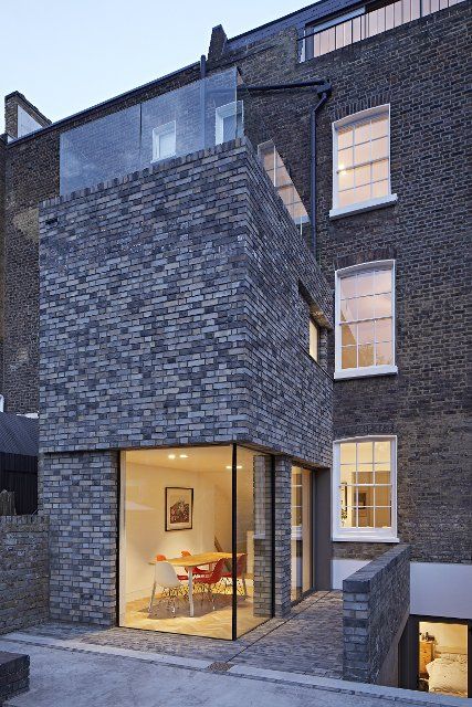 Overall dusk view of double-height rear extension with corner window on ground level. Queens House, London, United Kingdom. Architect: Paul Archer Design - Architects & Design, 2021