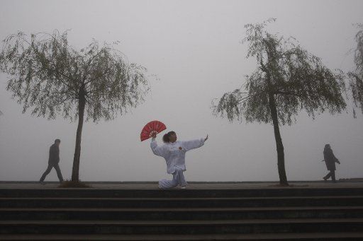 (101221) -- SUINING Dec. 21 2010 (Xinhua) -- A woman does morning exercise on a foggy day in Suining City southwest China\