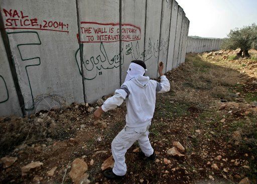 (110114)-- RAMALLAH Jan. 14 2011 (Xinhua) -- A Palestinian protester hurls stones at Israeli soldiers during a protest against the Israeli controversial barrier in the West Bank village of Nilin west of Ramallah on Jan. 14 2011. (Xinhua\/Fadi ...
