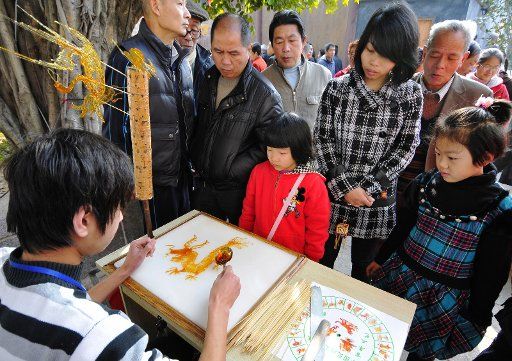 (110205) -- FUZHOU Feb. 5 2011 (Xinhua) -- People watch sugar painting performance in an ancient street in Fuzhou southeast China\