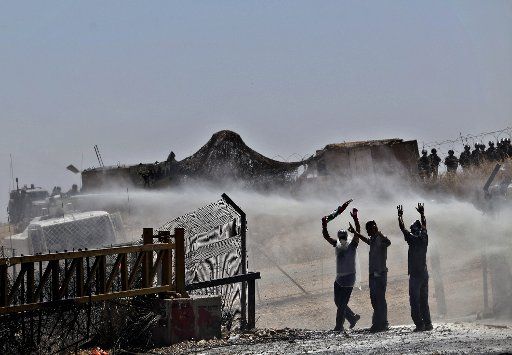(110617) -- WEST BANK June 17 2011 (Xinhua) -- Palestinian protesters wave sign victory as Israeli water cannon spray them by foul substance during a weekly protest against the controversial Israeli barrier in the West Bank village of Bilin near ...