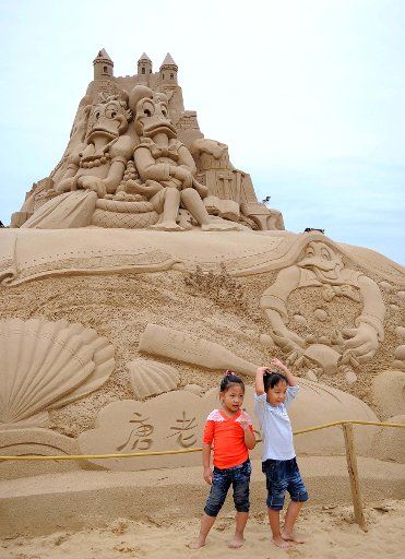 (110924) -- ZHOUSHAN Sept. 24 2011 (Xinhua) -- Photo taken on Sept. 24 2011 shows two kids posing by a sculpture of Disney cartoon characters in Zhoushan east China\