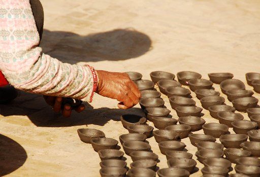 (121104) -- KATHMANDU, Nov. 4, 2012 (Xinhua) -- A woman dries clay oil lamps in sunlight for the upcoming Tihar festival in Bhaktapur, outskirts of Nepalese capital Kathmandu, Nov. 4, 2012. Tihar is the second largest festival of the Hindus. (...