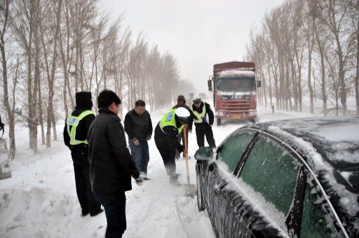 (121113) -- HOHHOT, Nov. 13, 2012 (Xinhua) -- Traffic policemen help move the trapped vehicle out of the snow-covered road in Naiman Banner of Tongliao City in north China\