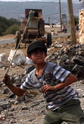 (121102) -- NABLUS, Nov. 2, 2012 (Xinhua) -- A Palestinian protester throws stones at Israeli soldiers during a protest against the expanding of Jewish settlements in Kufr Qadoom village, near the West Bank city of Nablus on Nov. 2, 2012, the ...