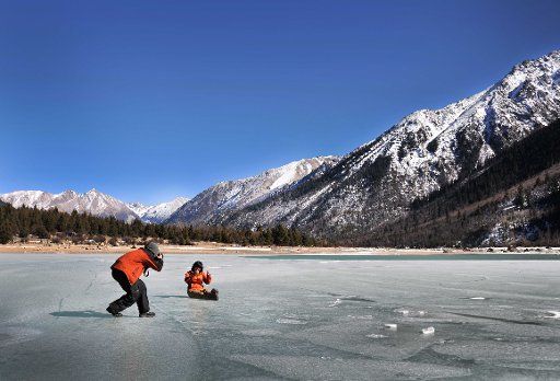 (130102) -- NYINGCHI, Jan. 2, 2013 (Xinhua) -- A tourist takes a photo on the frozen Rawok Lake, a famous scenic spot in Baxoi County, southwest China\