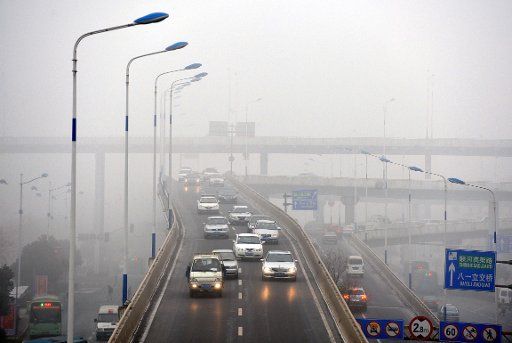 (130115) -- JINAN, Jan. 15, 2013 (Xinhua) -- Motorcars run on a road amid fog in Jinan, capital of east China\