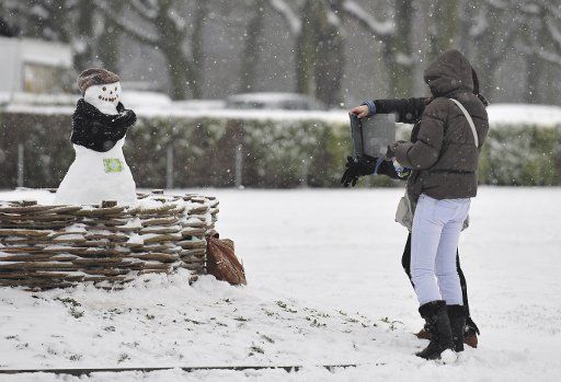 (130115) -- BRUSSELS, Jan. 15, 2013 (Xinhua) -- Girls take photos of a snowman at a park in Brussels, capital of Belgium, Jan. 15, 2013, after a heavy and overnight snowfall. (Xinhua\/Ye Pingfan)