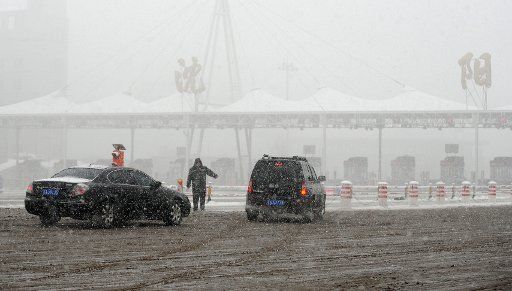 (130312) -- SHENYANG, March 12, 2013 (Xinhua) -- A working staff directs vehicles to move in snow at a highway entrance in Shenyang, capital of northeast China\