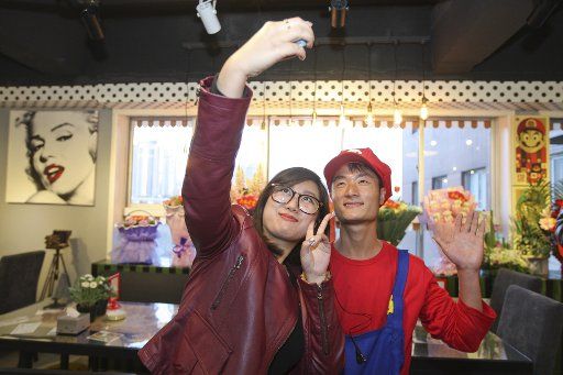 (130408) -- TIANJIN, April 8, 2013 (Xinhua) -- A waiter in the costume of Super Mario, a famous video game character, poses for photos with a customer at a Mario themed restaurant in Tianjin, north China, April 8, 2013. The restaurant that opened on ...